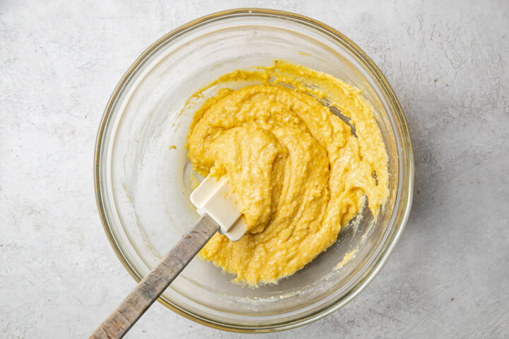 Wet and dry ingredients for paleo pancakes in a glass mixing bowl with a silicone spatula.