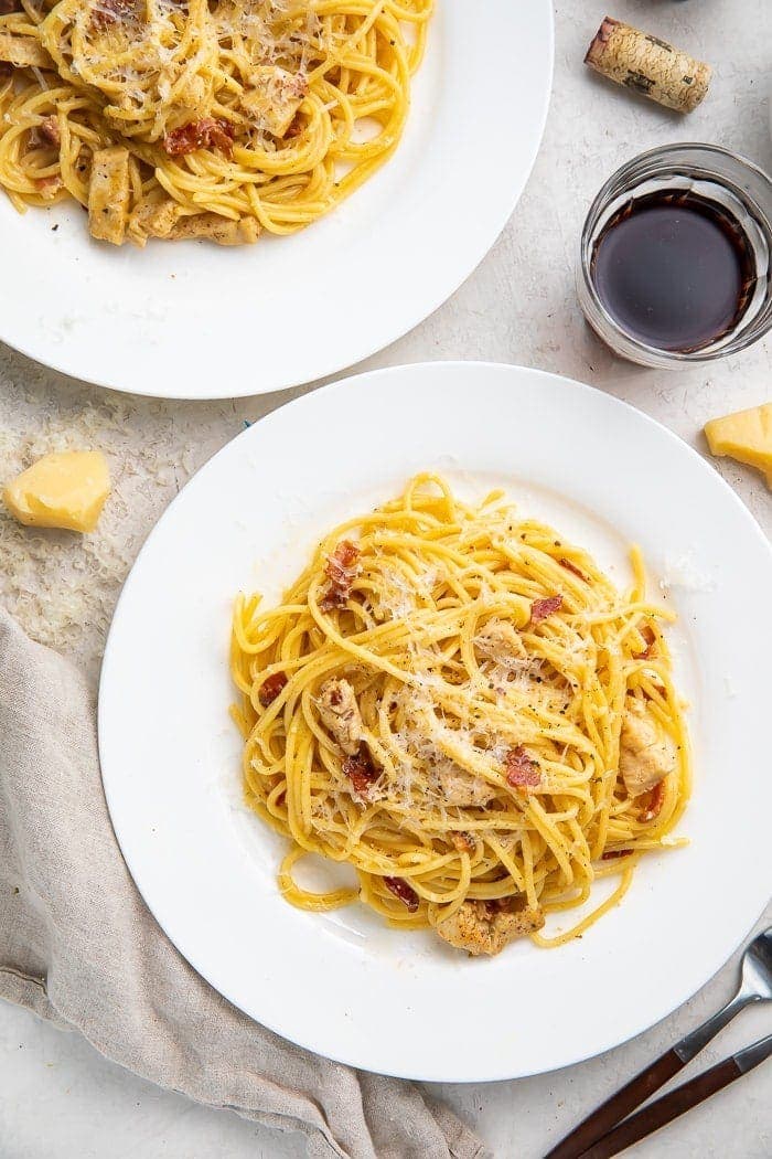 Chicken carbonara on a plate with a glass of red wine