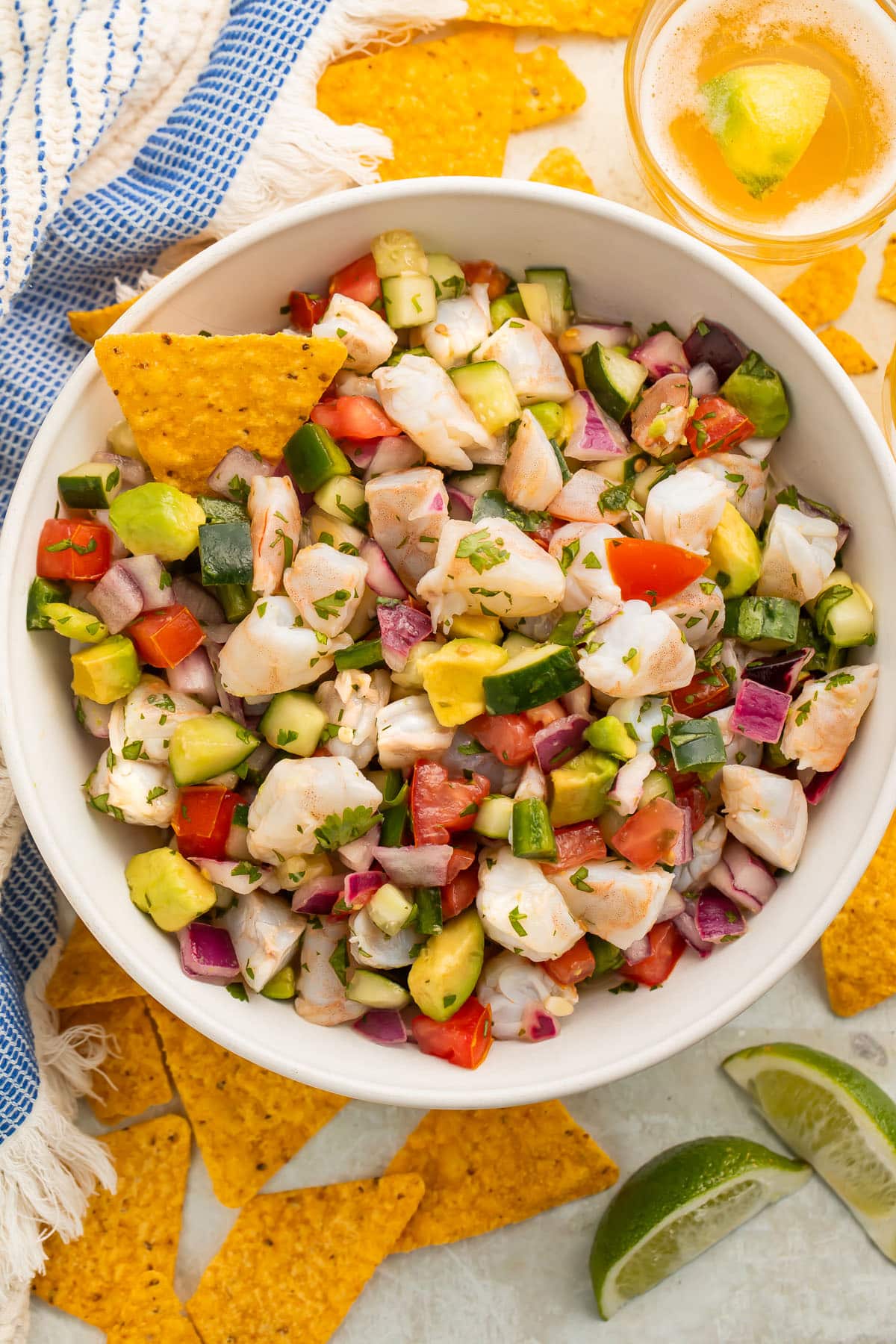 Overhead view of a bowl of easy shrimp ceviche with chunks of shrimp, red onion, cucumber, avocado, and tomatoes.