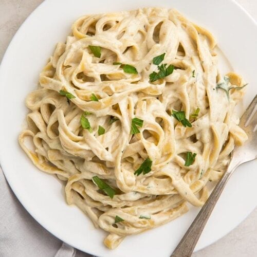 White plate of pasta with vegan alfredo sauce