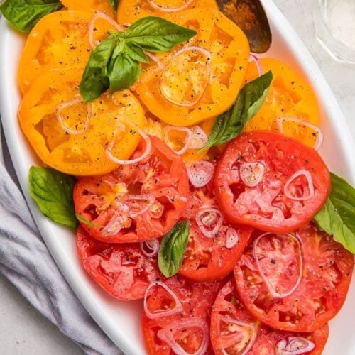 Slices of red and yellow heirloom tomatoes on a serving plate