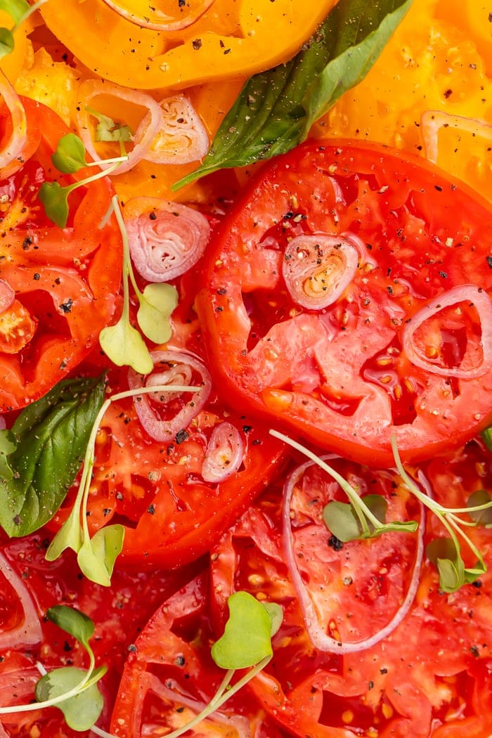 Close-up of red heirloom tomatoes covered with micro broccoli and shallots