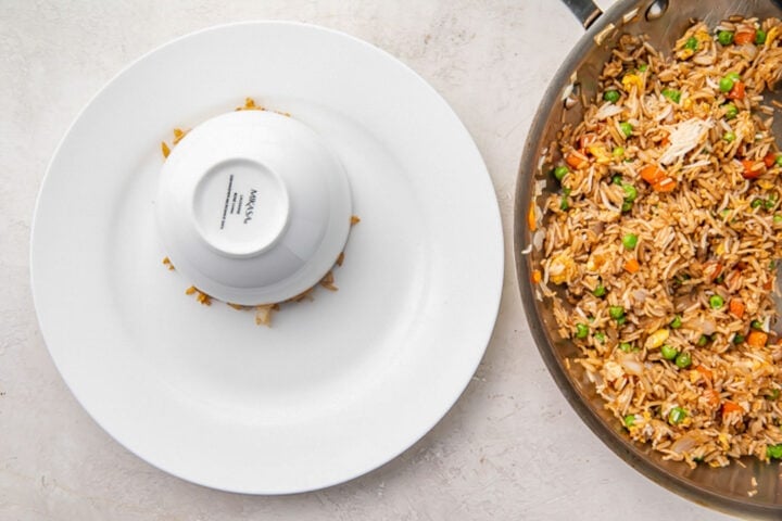 Cooled rice packed into a bowl upside down on a large white plate.