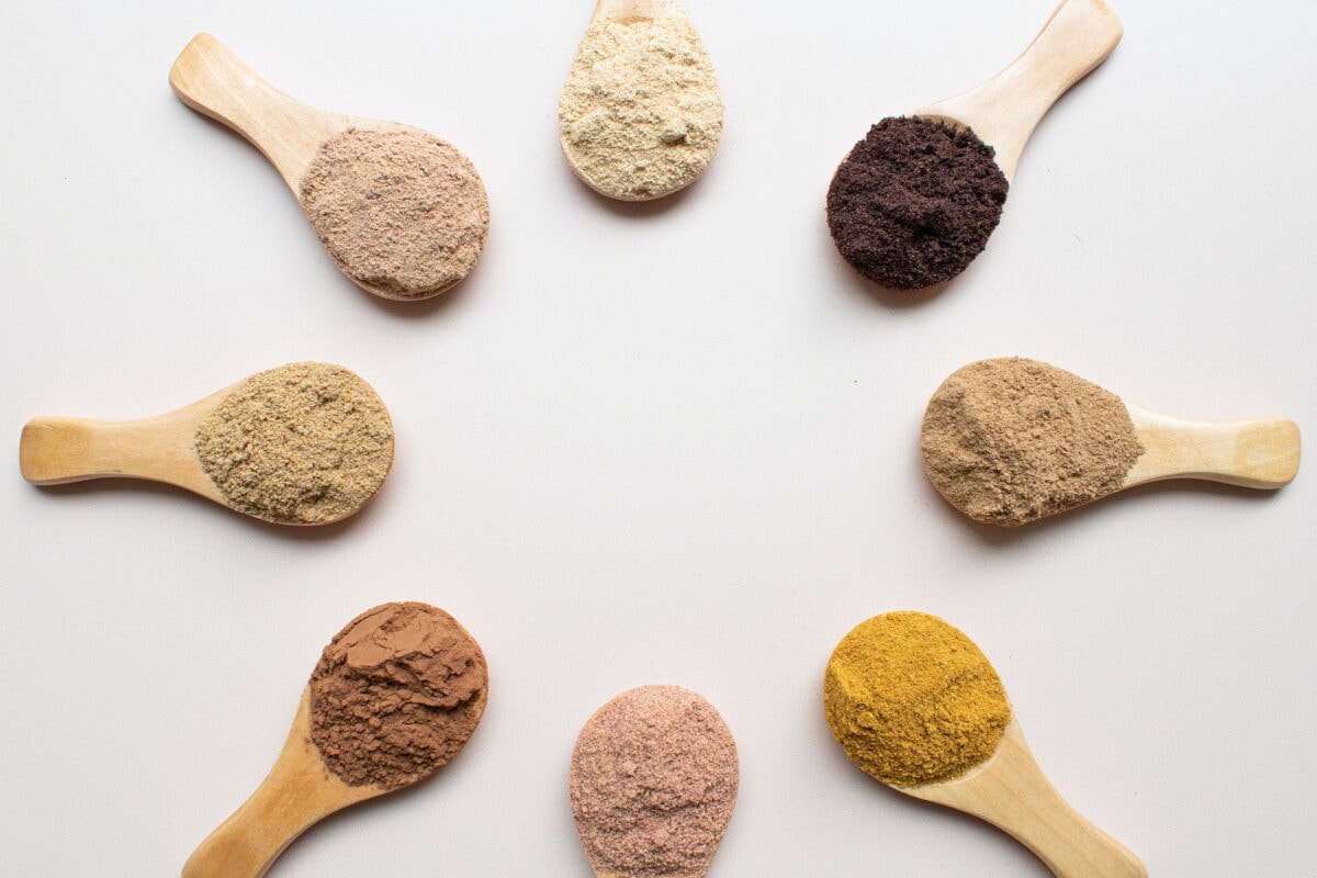 A circle of wooden spoons, each holding a different powdered supplement.