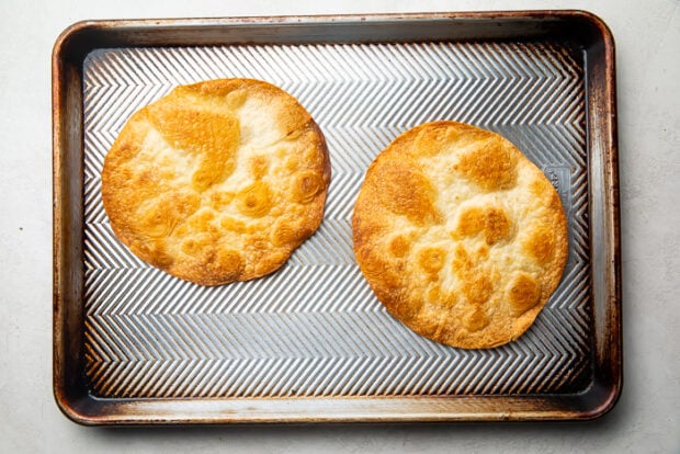 Two baked flour tortillas on top of a baking sheet