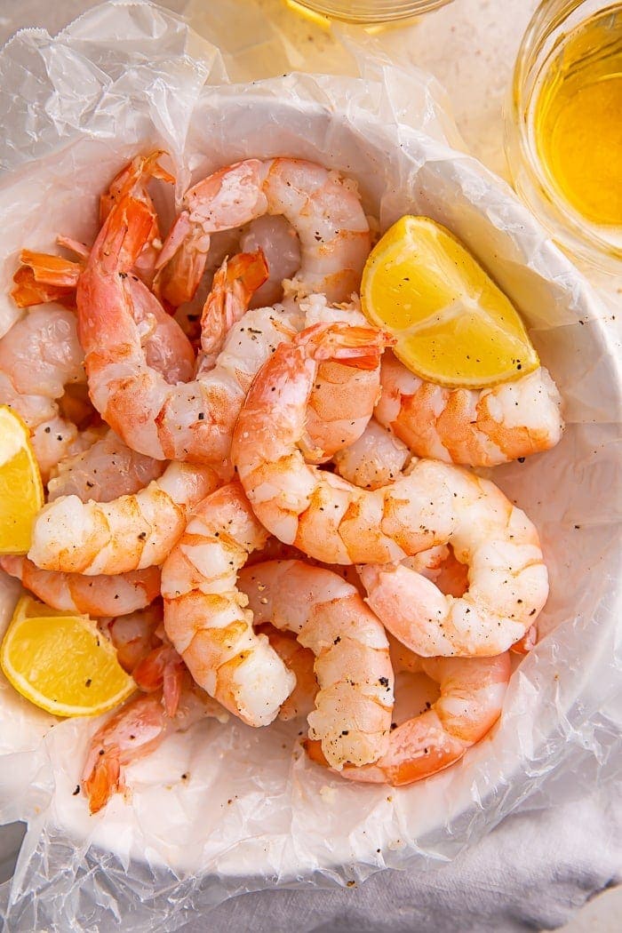 Instant Pot shrimp and lemon wedges inside a bowl lined with parchment paper