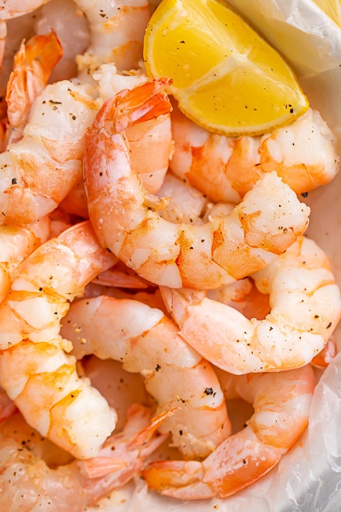 Close-up of Instant Pot shrimp and a lemon wedge on a piece of parchment paper