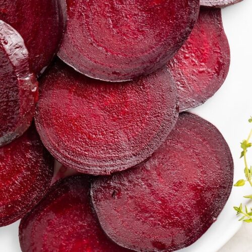 Dark red beets cut into medallions displayed on a white dish