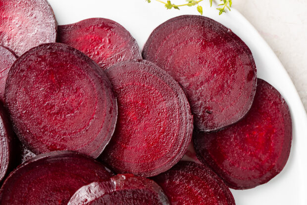 Dark red roasted beet medallions on white dish