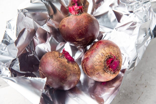 Whole beets with trimmed stem on sheet of aluminum foil