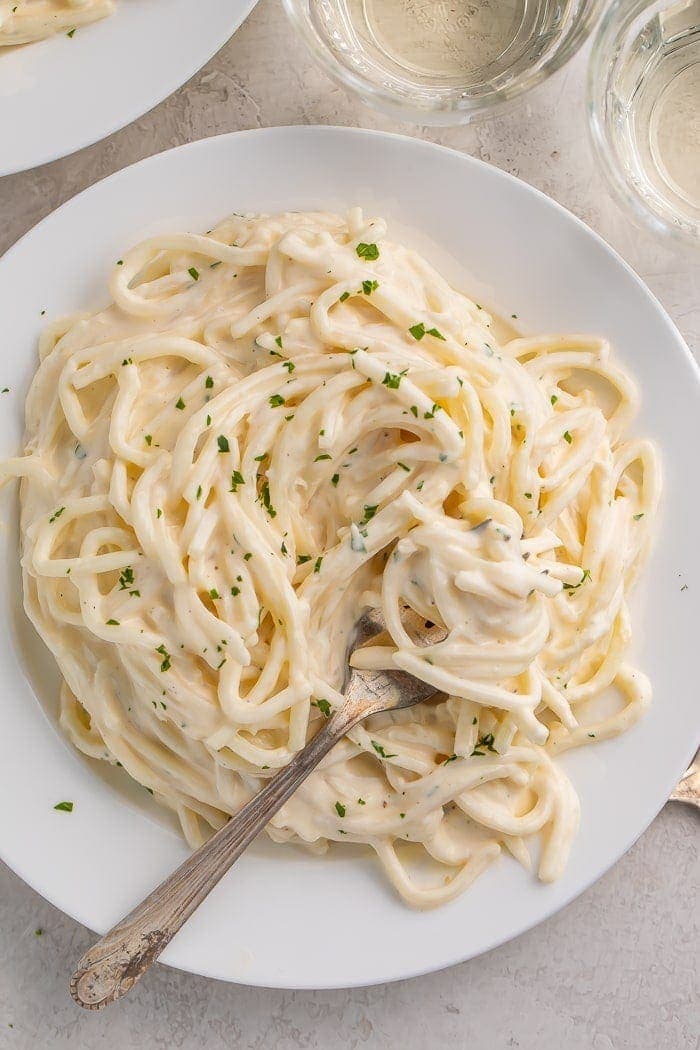 Pasta with keto alfredo sauce on a white plate with a fork