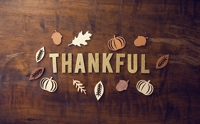 Thankful spelled on in cut-out letters on a wooden table