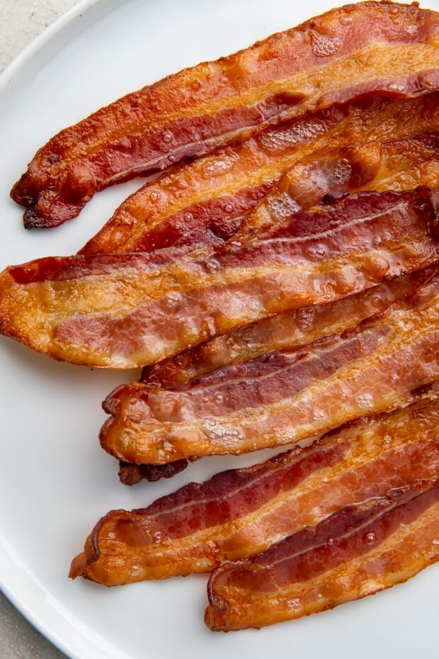 Strips of oven-cooked bacon on a white plate