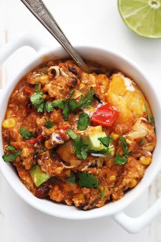 A white bowl of vegetarian slow cooker enchilada quinoa with a spoon