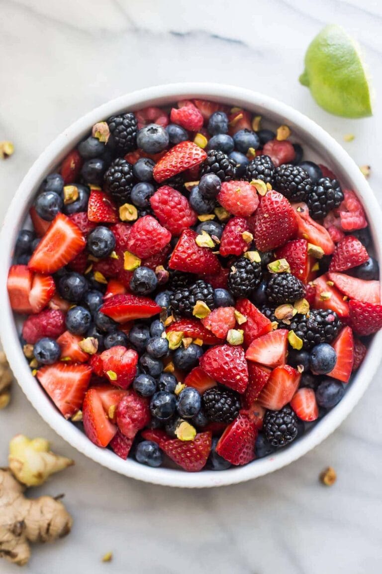 White bowl of mixed berries, ginger, lime, and mint