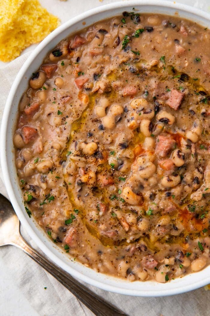 White bowl holding instant pot black eyed peas with ham, bacon, and onion