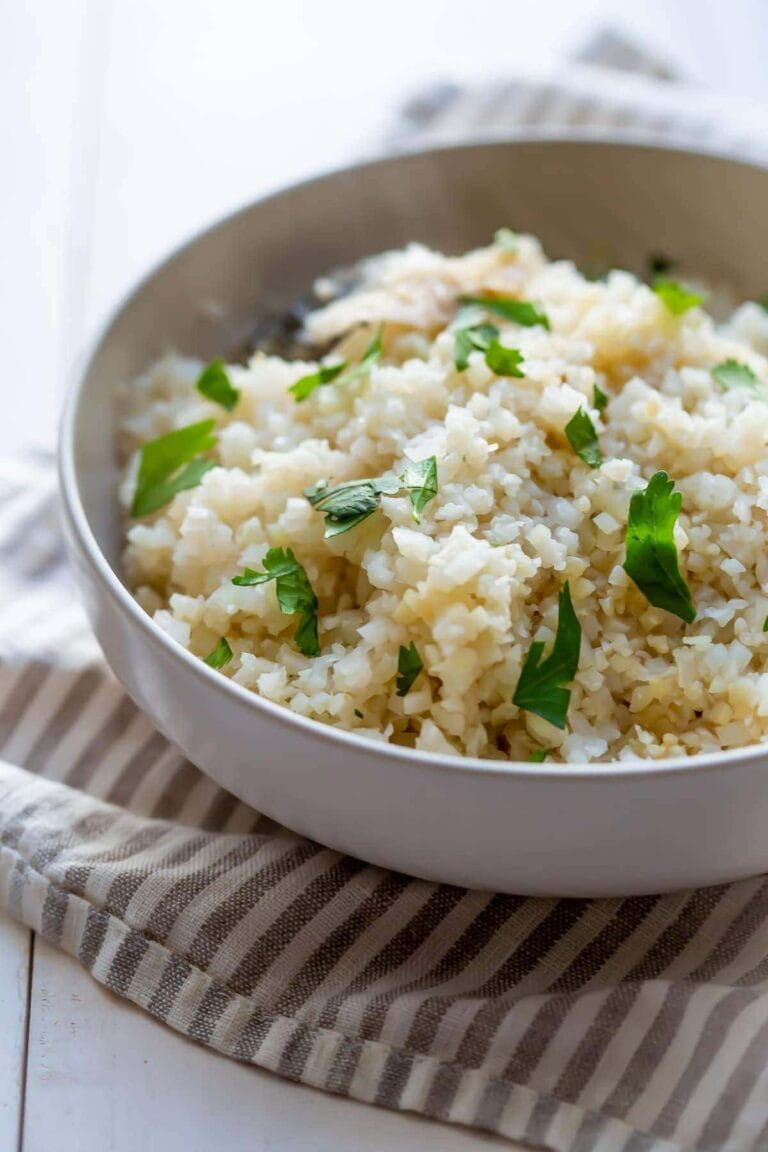 A white bowl containing jasmine cauliflower rice garnished with cilantro