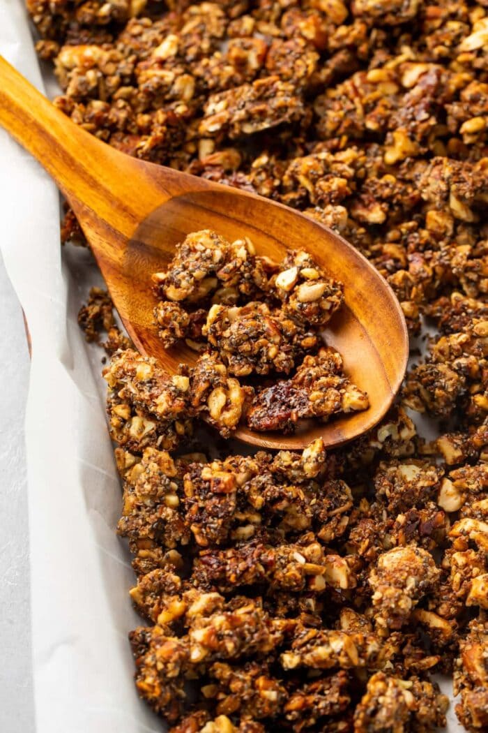 Baked keto granola on a sheet pan with a wooden spoon