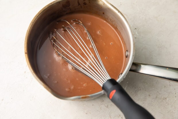 Chocolate chips, swerve, cocoa powder, and heavy cream keto hot chocolate in a saucepan with whisk