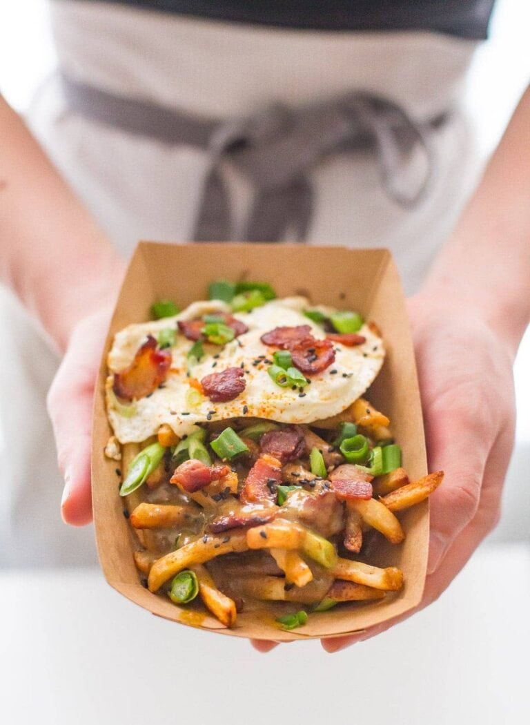 Paleo curry fries topped with an egg inside paper box.