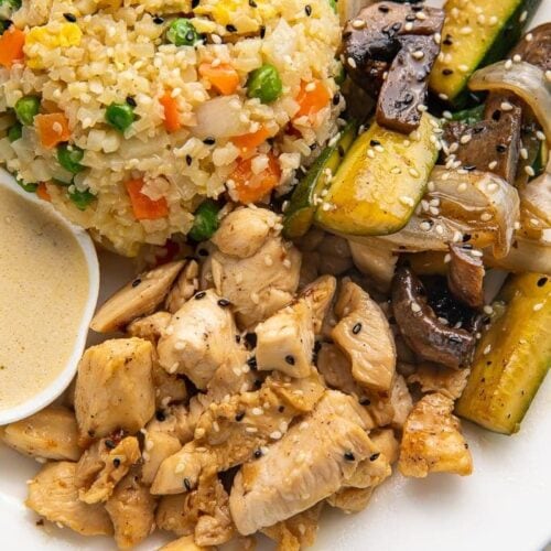 Close up photo of whole30 hibachi chicken, rice, and veggies on a white plate