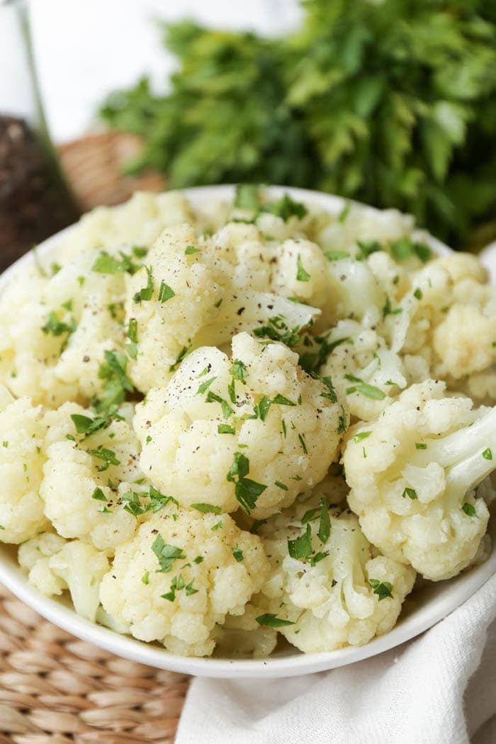 A white bowl of cauliflower florets with garnish