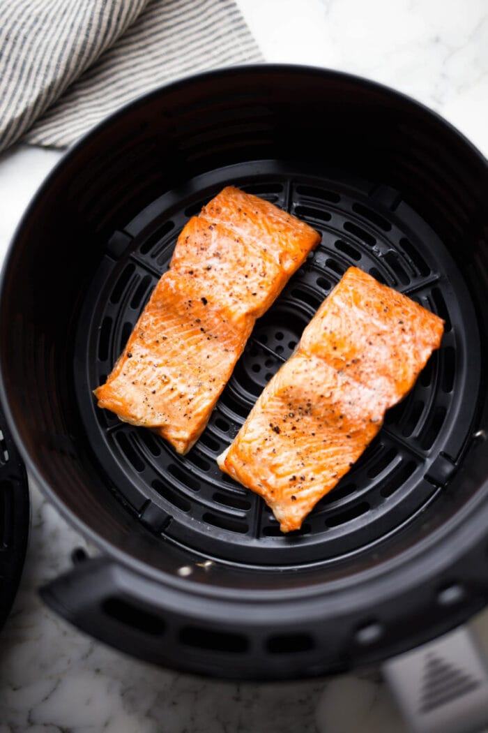 Two pieces of salmon in an air fryer basket