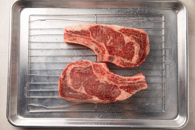 Seasoned ribeyes on a wire rack