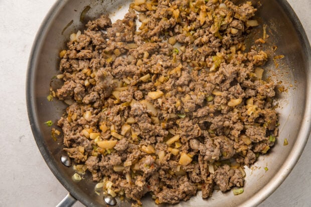 Ground pork, ginger, water chestnuts, and sriracha in a silver saucepan