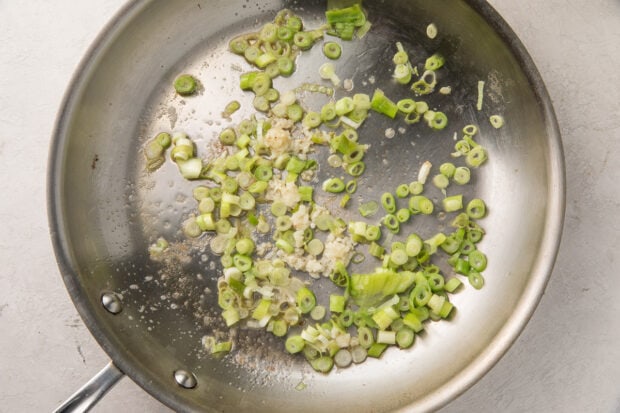 Garlic and green onion sauteed in a silver saucepan