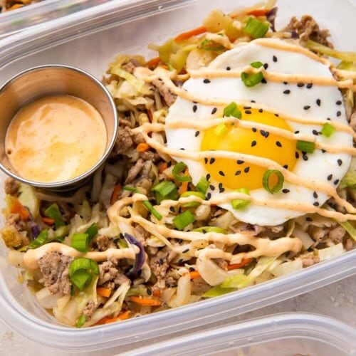 Close up of Egg roll in a bowl with a fried egg in meal prep containers