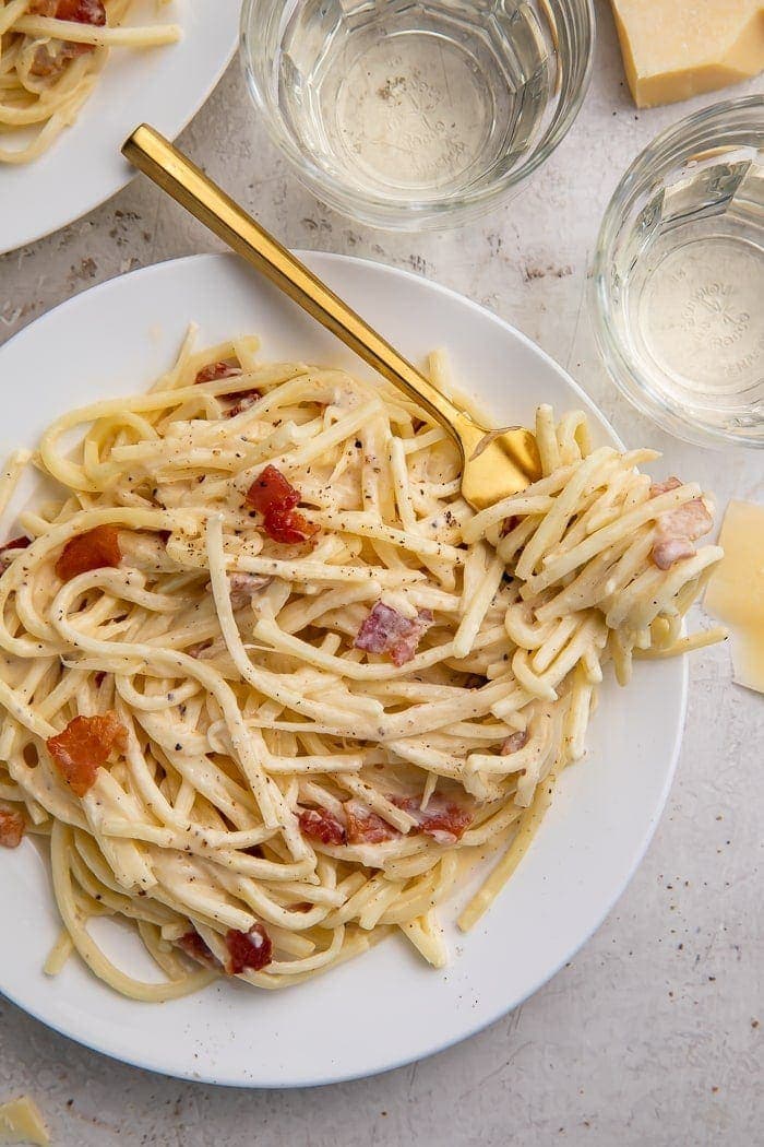 A white plate of keto carbonara with a golden fork