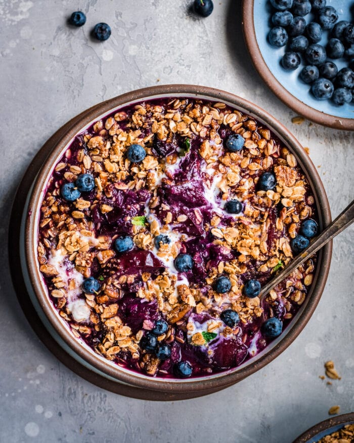 A brown bowl containing vegan Instant Pot nectarine berry crisp on a grey table