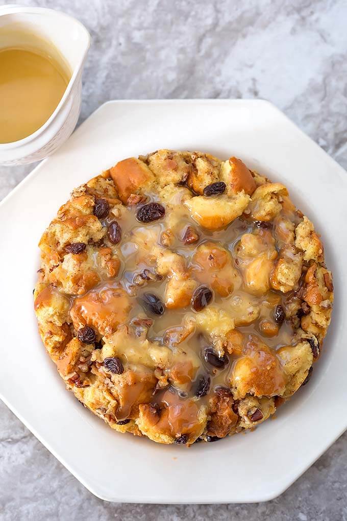 A white plate on which sits a vegan bread pudding and sauce made in the Instant Pot