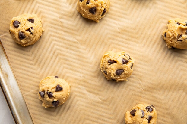 Cookie dough balls on a baking sheet lined with parchment paper