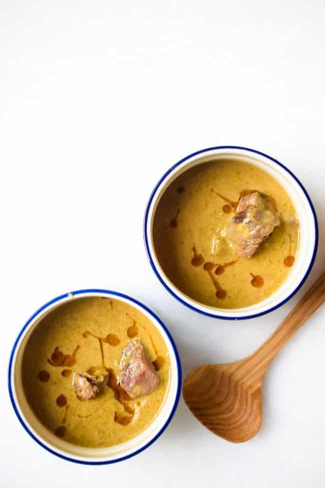 Two bowls of beef and broccoli soup on a white background