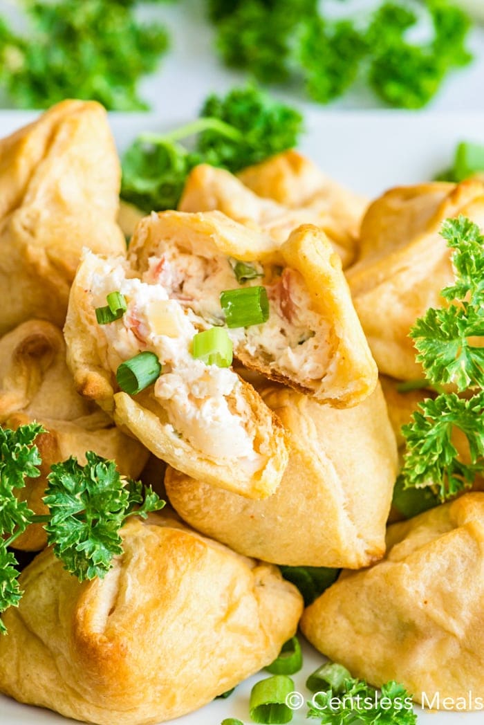 Crescent roll pile with the top crescent roll torn in half to show cream cheese mixture