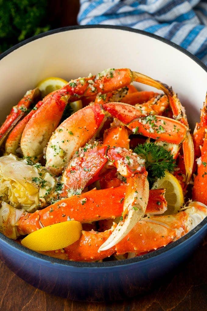 A big pot of bright red crab legs with yellow lemon wedges