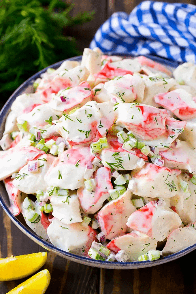 A large bowl of crab salad with a blue and white striped napkin in the background