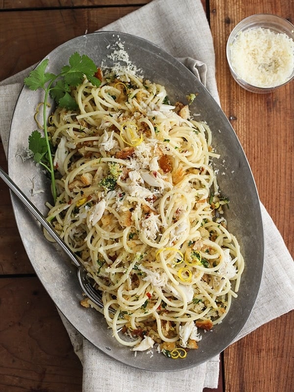 A dark silver oval-shaped platter with spaghetti and crab