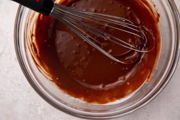 Melted chocolate in a glass bowl with a whisk