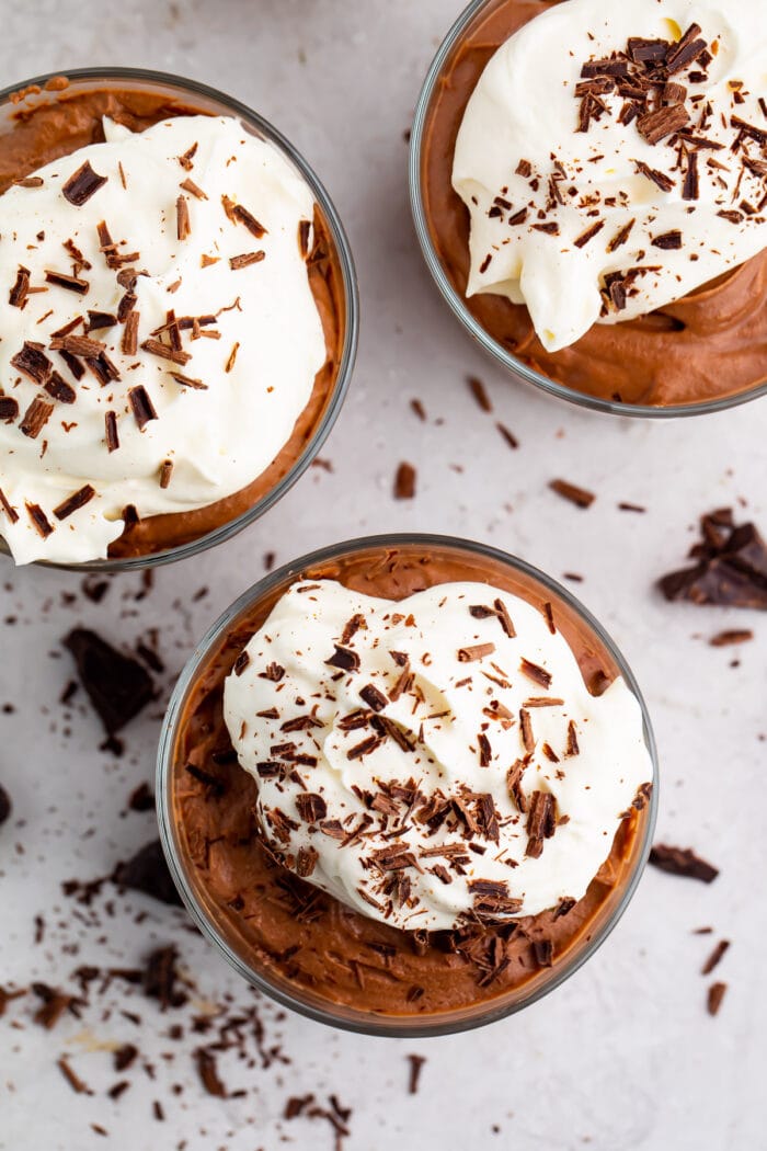 3 small glass cups of keto chocolate mousse with whipped cream and chocolate shavings