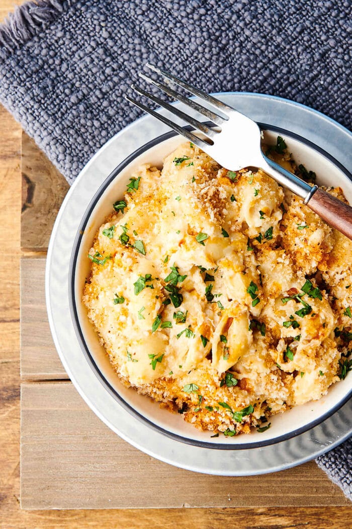 A white bowl of mac and cheese with breadcrumbs and garnish