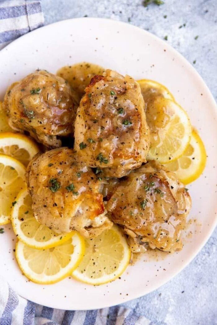 Chicken on top of slices of lemon, on a white plate