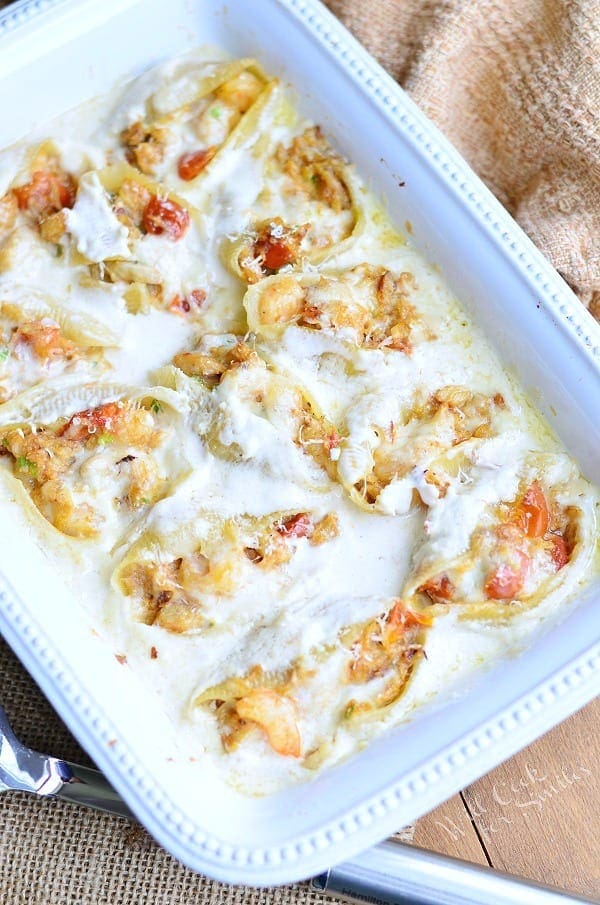 A large white casserole dish containing seafood stuffed pasta shells with sauce