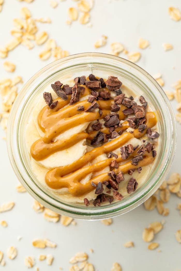 Peanut butter oatmeal topped with chocolate chips and a banana in a glass jar