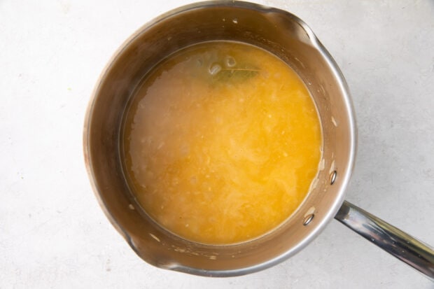 Fish stock with garlic, onion, and bay leaf in a large saucepan