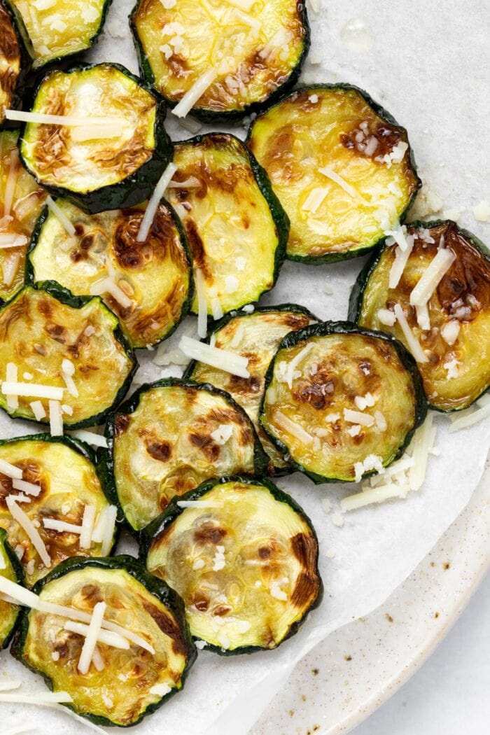 Overhead image of air fried zucchini slices with parmesan cheese on top.