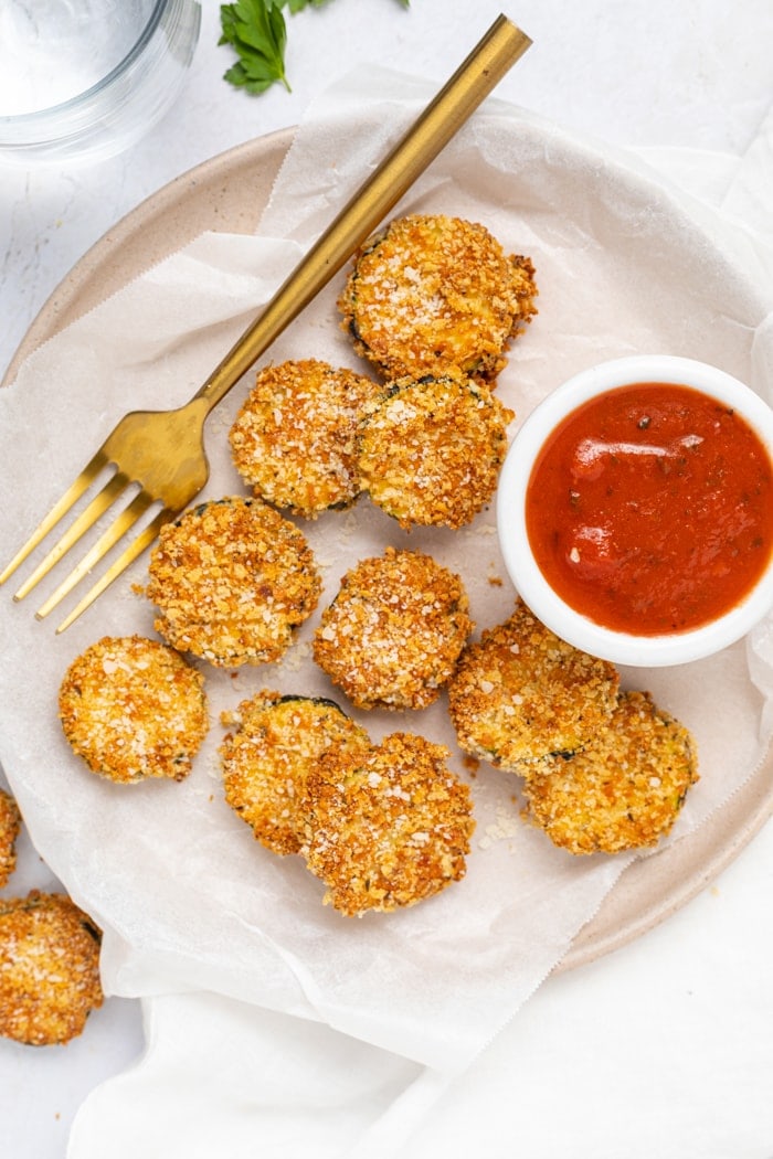 Air Fryer Zucchini Chips on a plate with a fork and a side of marinara sauce.