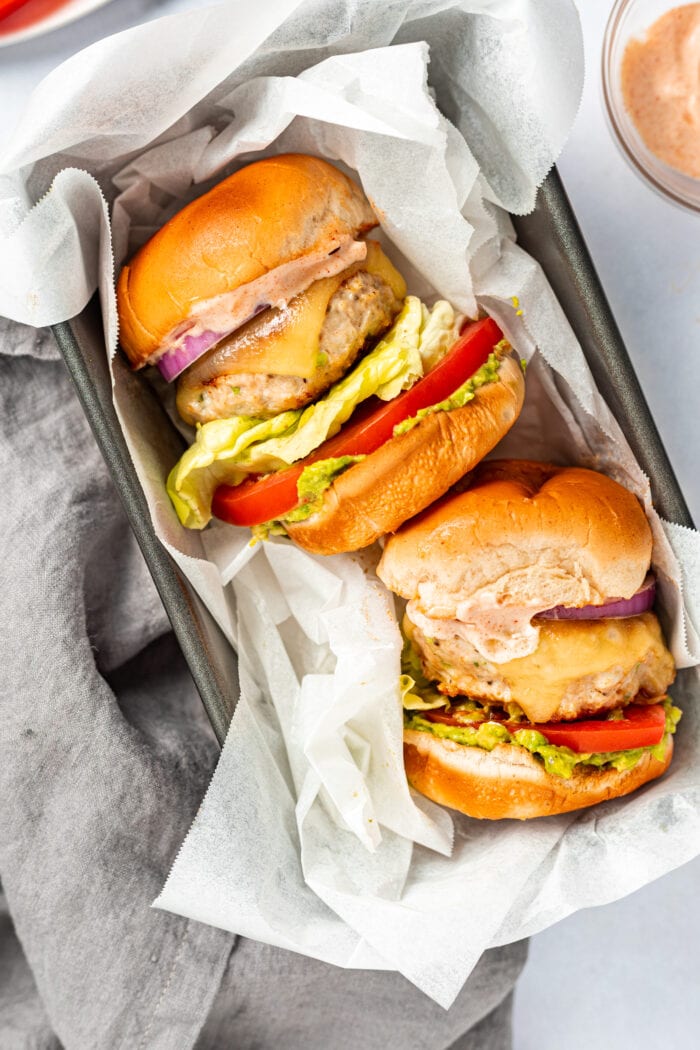 Two chicken burgers with chipotle aioli stacking inside of a loaf pan.